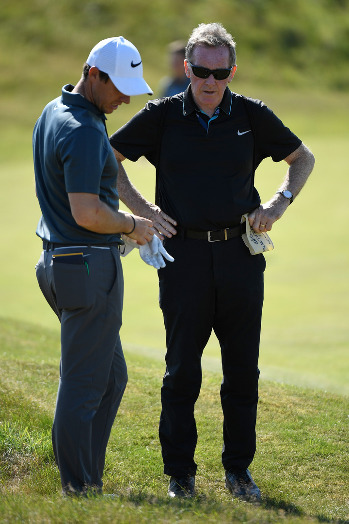 Rory McIlroy discussing strategy with his coach during a practice session.