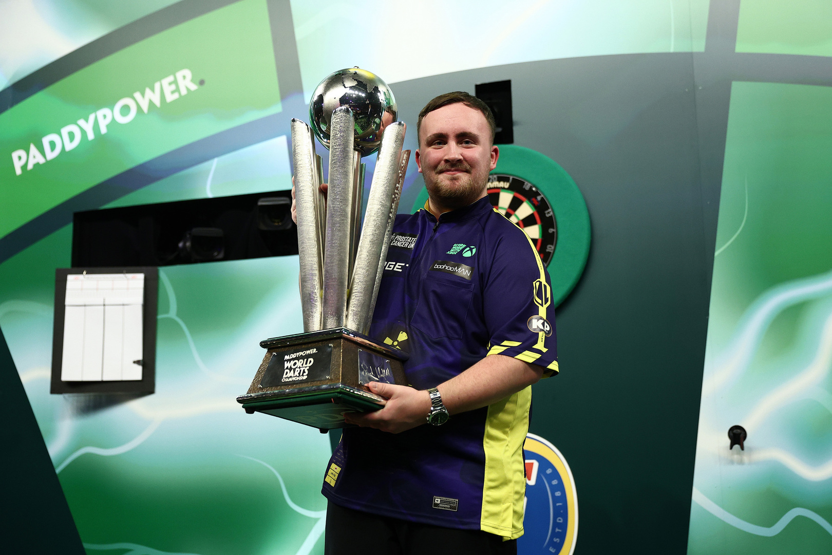 Darts player holding World Darts Championship trophy.